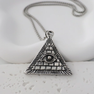 Macro detail of vintage silver-tone triangle evil eye pendant on a white stone background