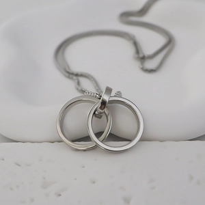 Detailed close-up of double interlocking rings pendant on a fine silver-tone chain