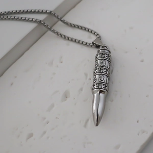 Vue macro du pendentif balle argentée avec mantra bouddhiste gravé et cylindre rotatif