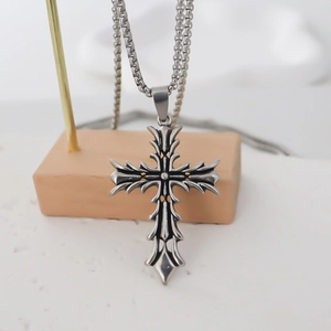 Detail of vintage silver gothic cross pendant with relief patterns on a wooden stand