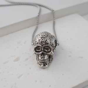 Primer plano del colgante de calavera plateada con intrincados grabados calados