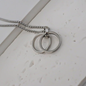 Close-up of a silver stainless steel interlocking double ring pendant on a box chain
