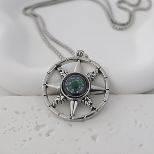Pendentif boussole vintage en argent avec aiguille verte sur fond de pierre blanche