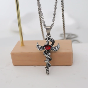 Macro detail of gothic pendant with winged cross, snake, and heart gemstone