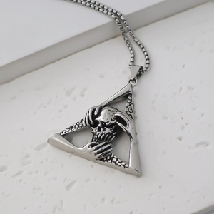 Macro detail of triangle skull pendant with embossed skeleton on stainless steel necklace