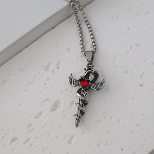 Macro detail of gothic sword and wings pendant with a central red heart gemstone