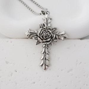 Macro shot of silver gothic cross pendant featuring a rose carving and ornate edges