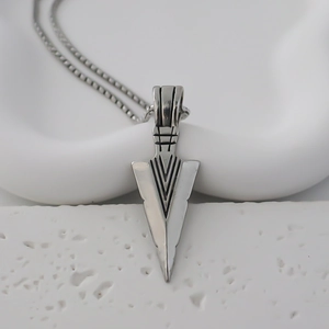 Detailed view of silver triangle arrow pendant with geometric carvings on a box chain
