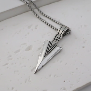 Macro shot of vintage silver arrowhead pendant with textured V-groove and box chain details