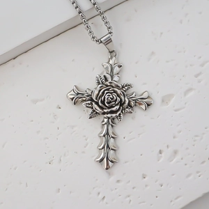 Close-up of vintage silver cross pendant with a central rose on a white stone background