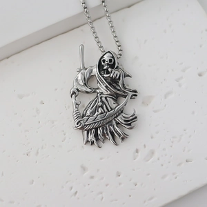 Detailed view of vintage silver grim reaper skull pendant on volcanic rock display