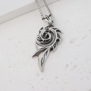 Détail d'un pendentif flamme tribale en argent vintage sur une chaîne à mailles carrées