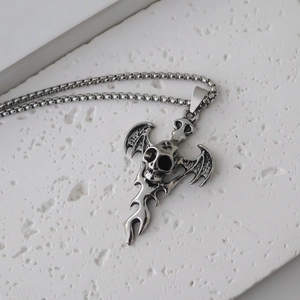 Macro detail of punk gothic bat skull pendant with intricate flame carvings on silver metal