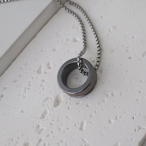 Vue latérale macro d'un pendentif anneau gris en acier brossé sur une chaîne vénitienne