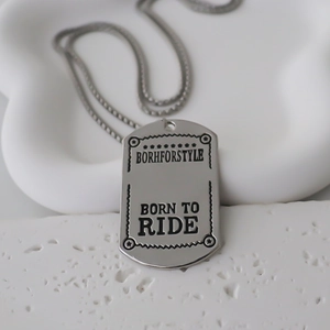 Detailed macro view of silver dog tag pendant with Born to Ride engraving on bead chain