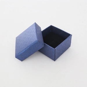 Détail d'un écrin à bijoux carré bleu foncé avec papier texturé et intérieur en velours