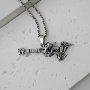Vue détaillée du pendentif crâne jouant de la guitare argenté sur support en pierre