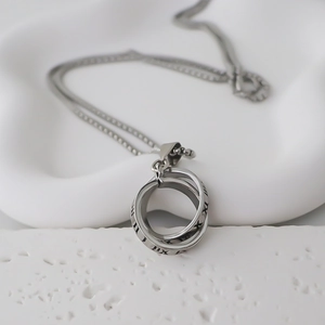 Collana con doppi anelli d'argento e numeri romani incisi su una base artistica bianca