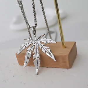 Vue macro d'un pendentif feuille d'érable poli avec nervures sur une chaîne fine
