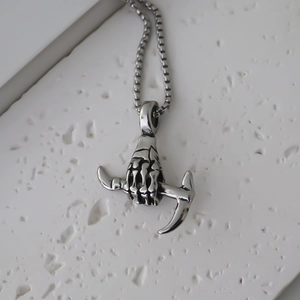 Macro detail of gothic skull hand pendant with box chain on a stone surface