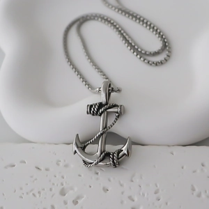 Macro shot of vintage silver anchor pendant with realistic rope details and square link chain