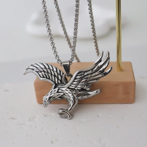 Collier avec pendentif aigle en acier inoxydable poli et chaîne box sur support bois