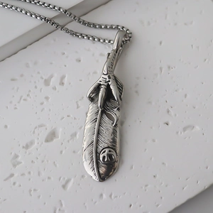 Dettaglio del ciondolo a piuma d'argento con artiglio d'aquila e catena su pietra