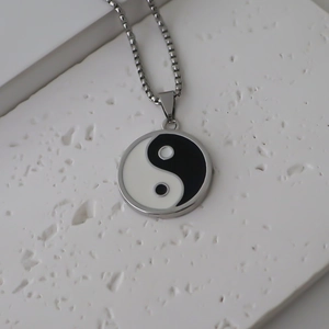Gros plan du pendentif Tai Chi Yin Yang en émail noir et blanc avec une chaîne en argent