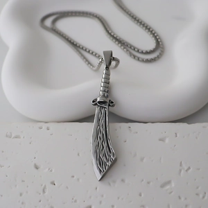 Close-up of a vintage stainless steel cleaver pendant on a classic silver link chain