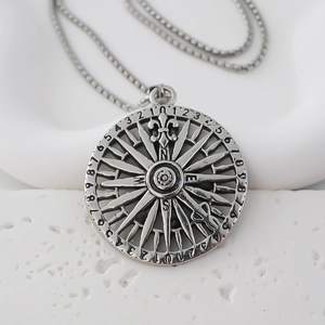 Macro detail of vintage compass pendant with N S E W markings and distressed silver finish
