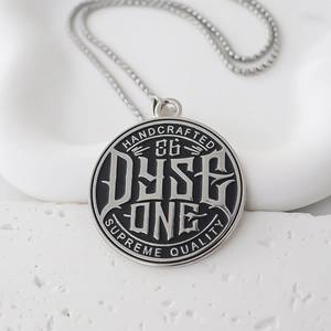 Close-up of industrial round metal pendant featuring Dyse One engraving and silver chain