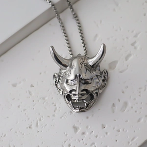 Detalle macro del colgante de máscara de demonio Hannya plateado vintage con cadena cuadrada