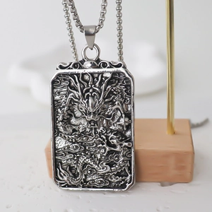 Vintage silver dragon pendant necklace with embossed square medallion on display stand