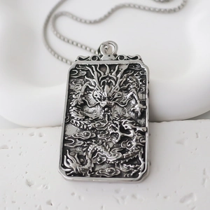 Detailed close-up of a silver dragon pendant with antique finish and sleek curb chain