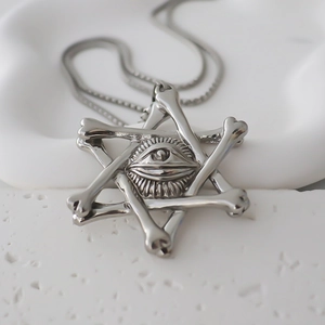 Macro shot of vintage silver hexagram pendant with all-seeing eye and bone motifs