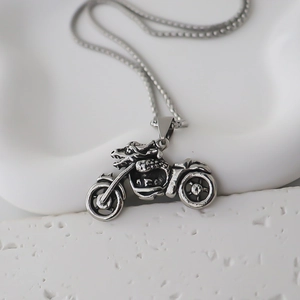 Detail of silver motorcycle pendant with dragon head design on a stainless steel chain