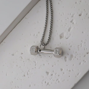 Vue macro du pendentif haltère en argent avec gravure Phil 4:13 et chaîne box élégante