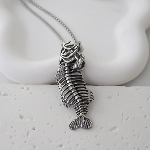 Detailed view of a vintage silver fish bone pendant on a textured white stone base