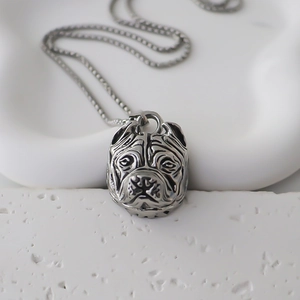 Macro shot of silver bulldog pendant with embossed details on a box chain necklace