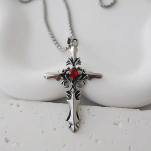 Macro view of gothic silver cross necklace with red gemstone and intricate retro texture