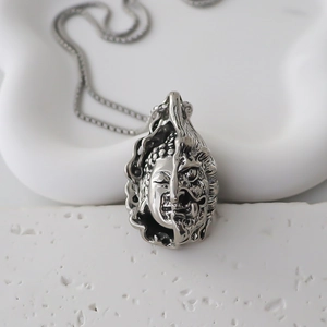 Détail macro du pendentif Bouddha et Démon argenté avec texture vintage sur chaîne