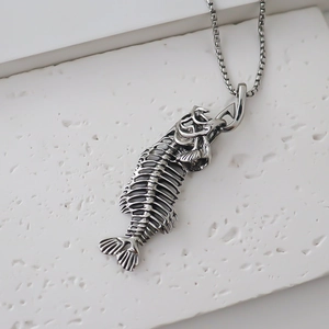Macro shot of an antique silver fish bone pendant on a square pearl chain necklace