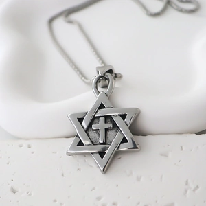 Close-up of a vintage silver hexagram pendant with a cross on a textured stone base