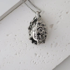 Détail macro du pendentif Bouddha-Démon double face argenté sur une surface en pierre