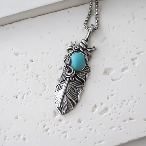 Macro shot of vintage silver feather pendant with turquoise stone and box chain detail