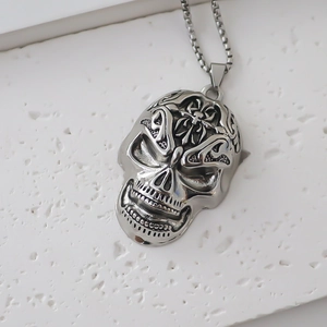 Gros plan du pendentif crâne punk avec gravure de croix sur fond de pierre blanche