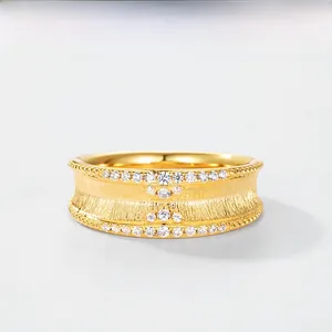 Gros plan sur une bague large en or brossé ornée de rangées de zircons brillants