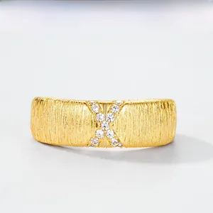 Macro shot of brushed gold finish band with crystal-encrusted X-shaped design detail