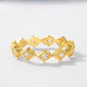 Detail of gold geometric rhombus ring with matte brushed finish and white zircons