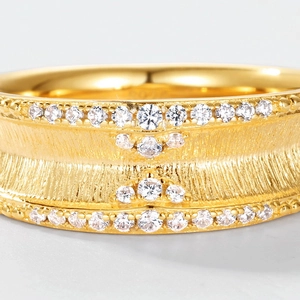 Macro d'une bague large plaquée or 18K avec texture écorce et diamants pavés